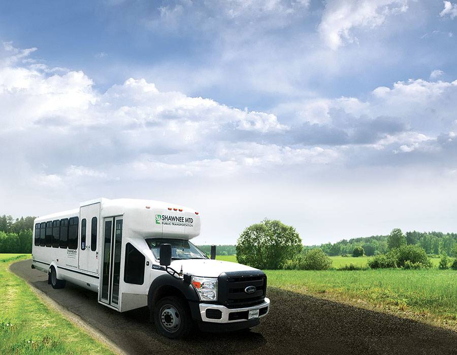 Shawnee Mass Transit bus sitting on a country road with blue skies and trees in the background