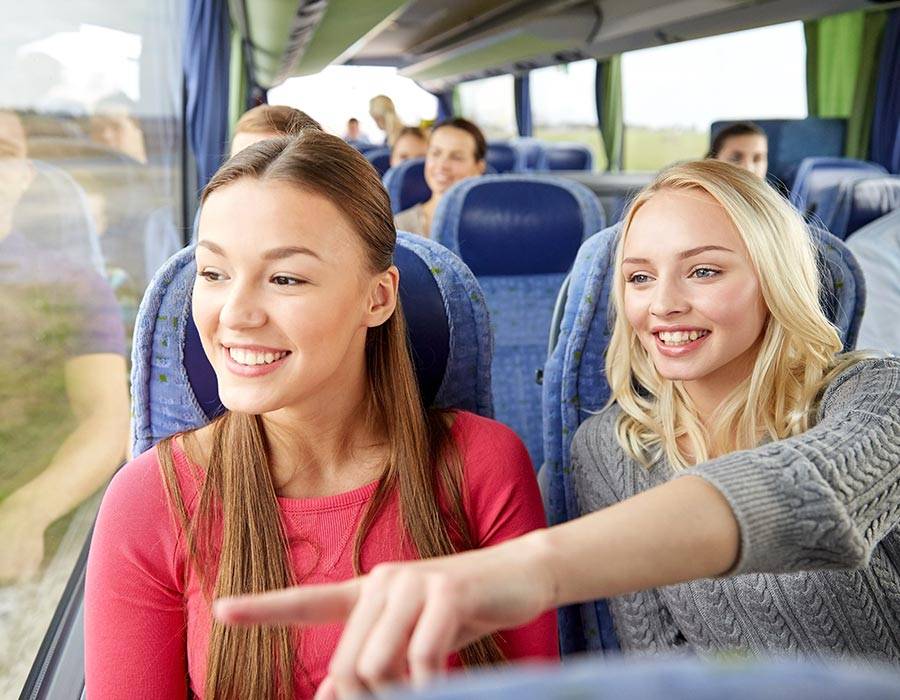 Two girls riding Shawnee Mass Transit bus and smiling while looking out of the window